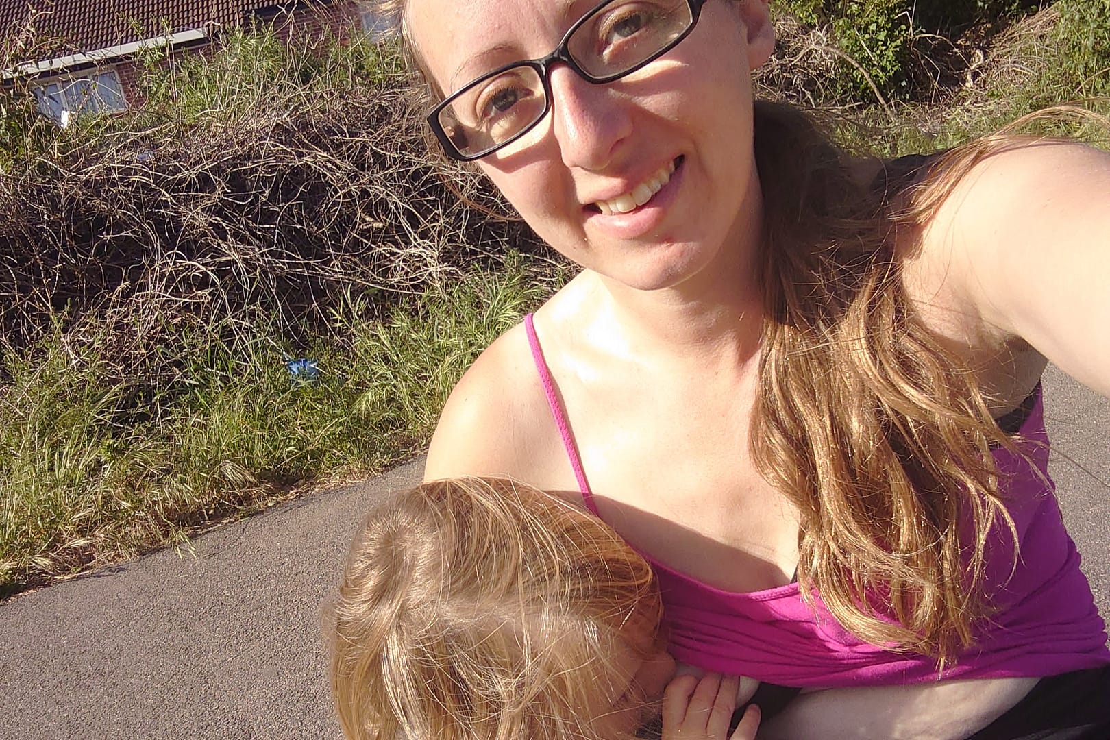 A mother breastfeeding her older child outdoors