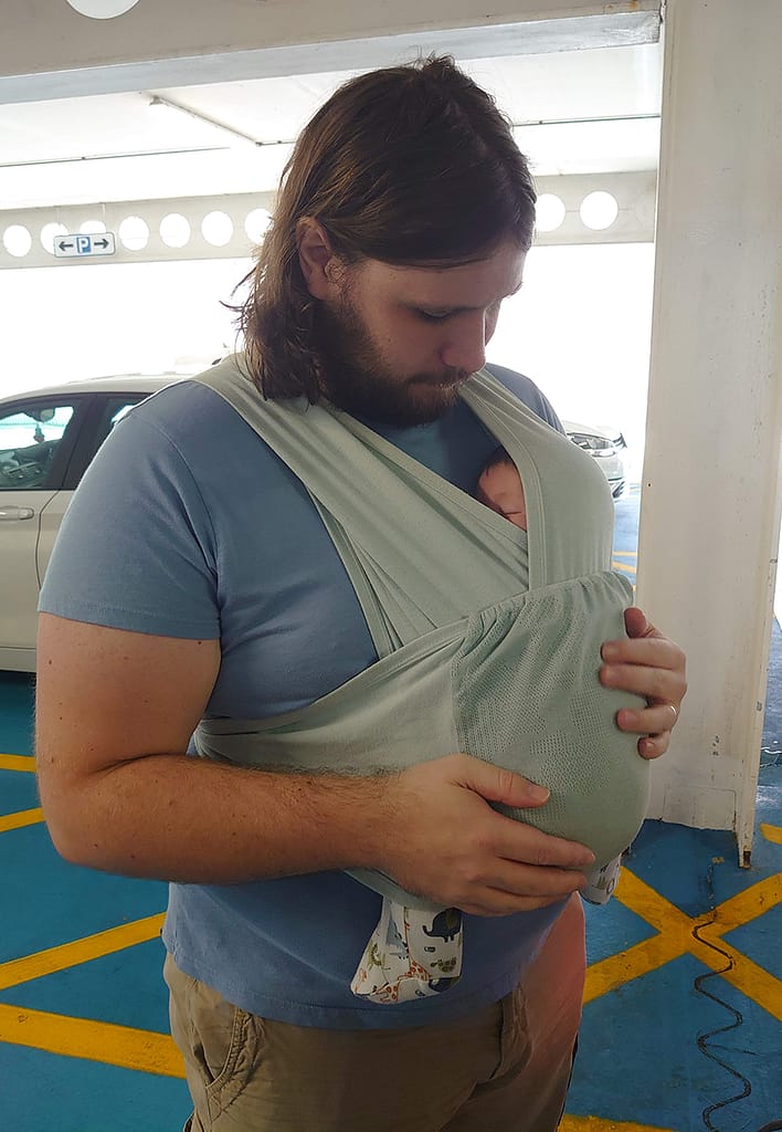 A dad carrying a baby in a sling