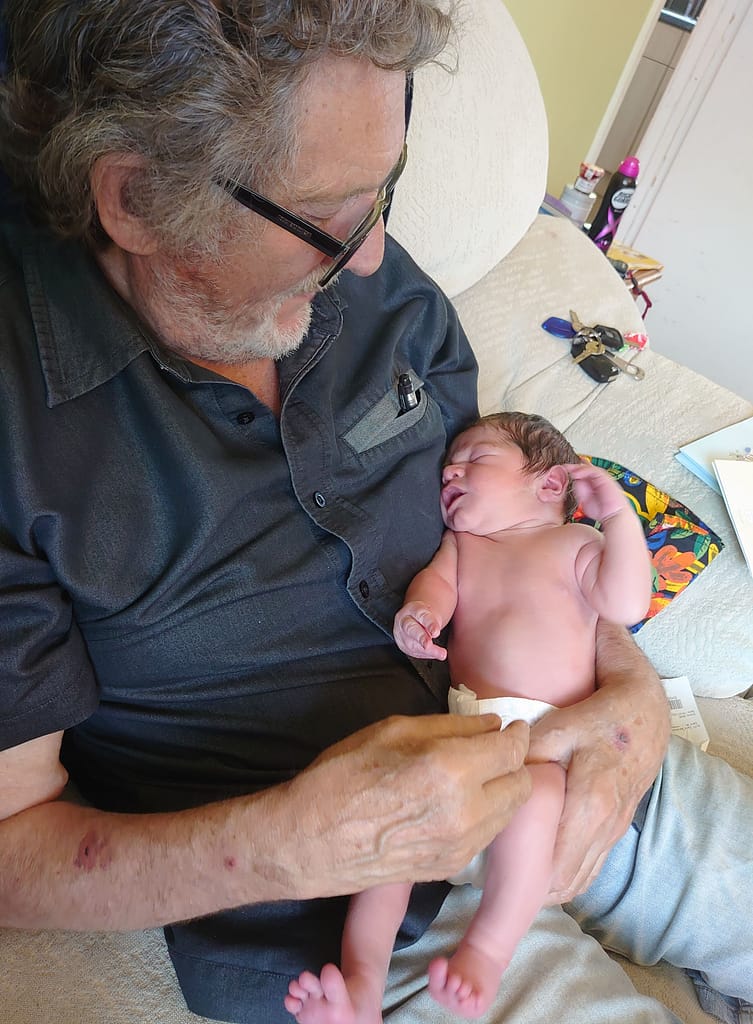A baby in a nappy being held by his grandad