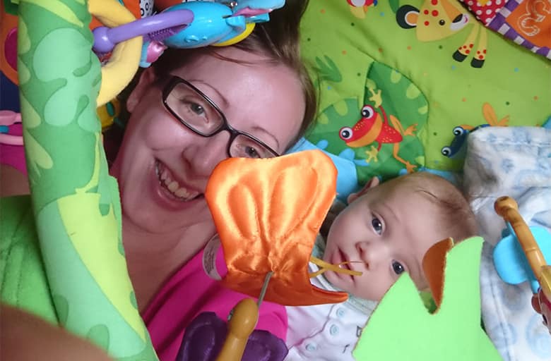 A mother and baby under a play gym