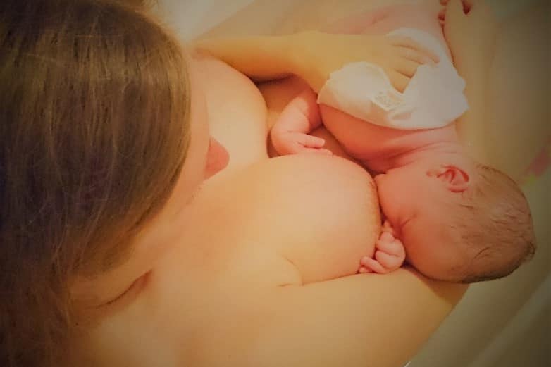 A mother breastfeeding a baby in the bath