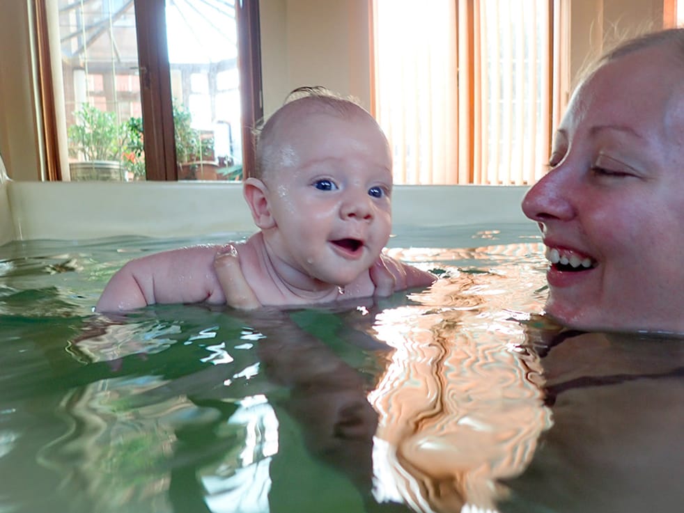 A baby being held in the water by his mother